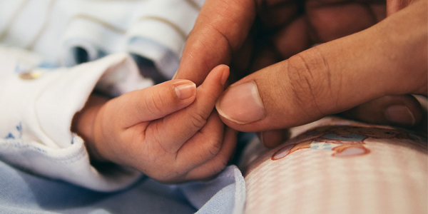 Kinderhand von Säugling greift nach Hand von Mutter